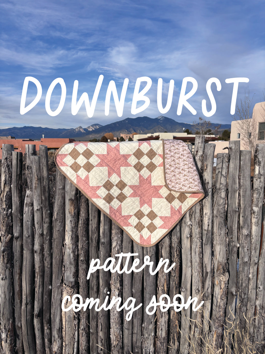 Quilt draped over a wooden fence with 'Downburst' pattern text and mountain background